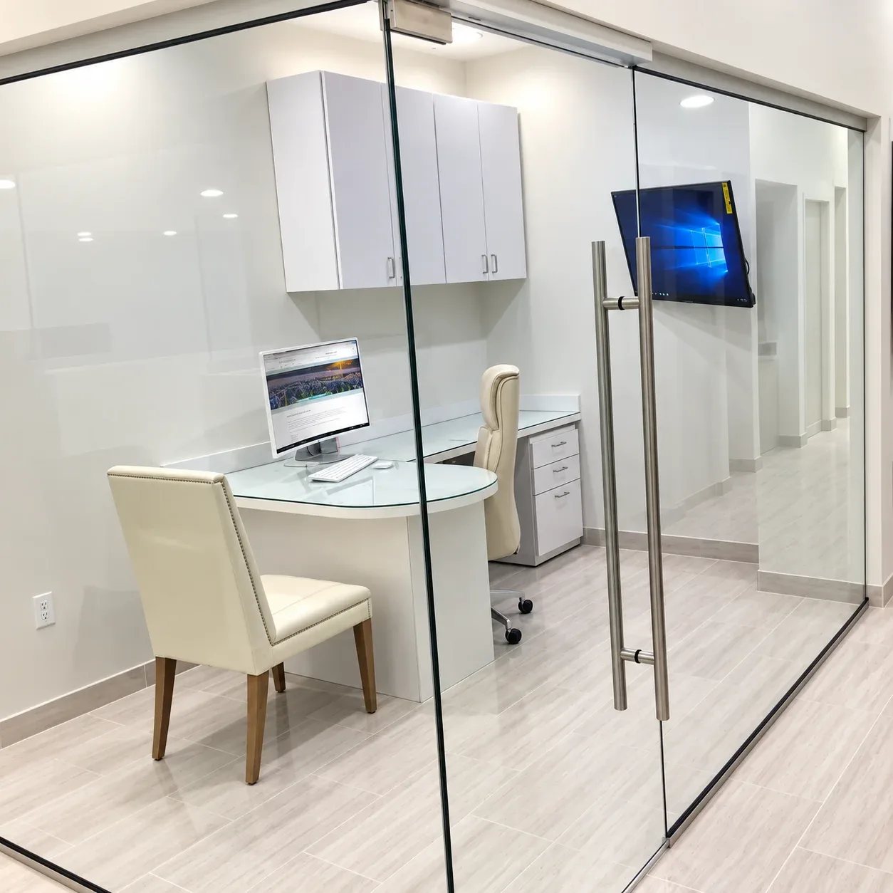 Glass-walled consultation office with cream chair and desk computer